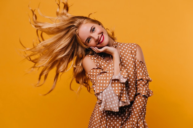 Debonair stylish woman waving her hair. Indoor photo of spectacular female model wears brown attire.