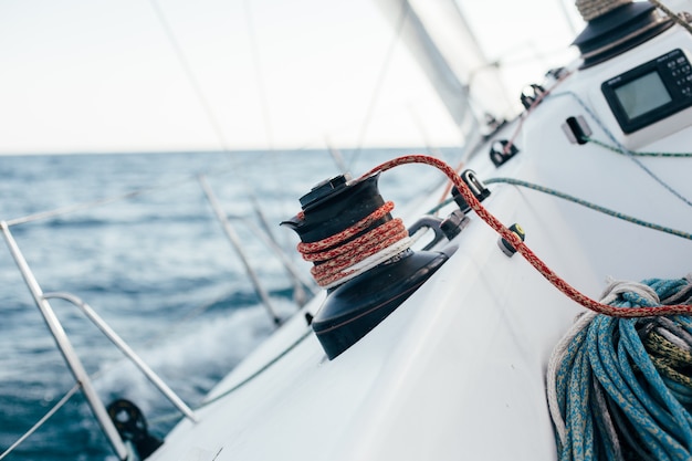 Deck of professional sailboat or racing yacht during competition on sunny and windy summer day, moving fast through waves and water, with spinnaker up