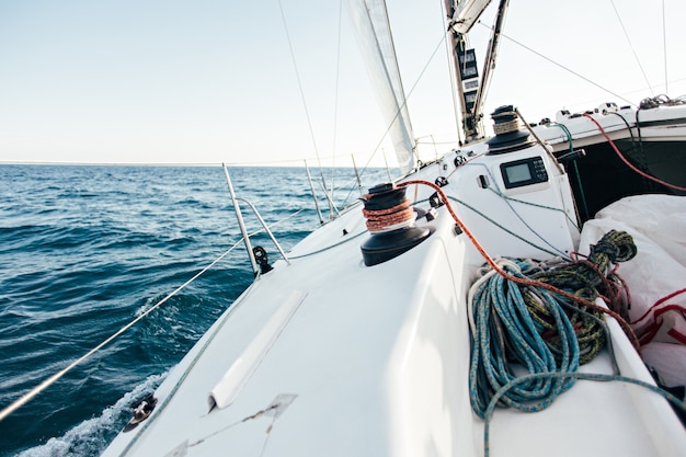 Free Photo deck of professional sailboat or racing yacht during competition on sunny and windy summer day, moving fast through waves and water, with spinnaker up