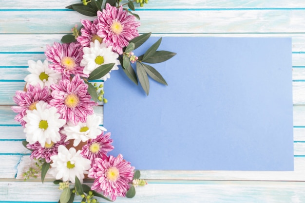 Free photo decorated flowers design on blank paper over the wooden table