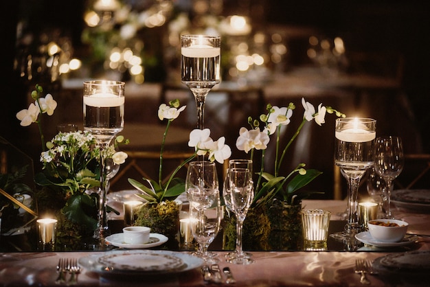 Decorated table with orchids and candles, glasses in the light