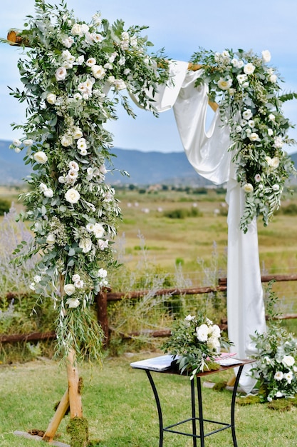 Free photo decorated wedding arch with greenery and white eustomas in the gardens outdoors