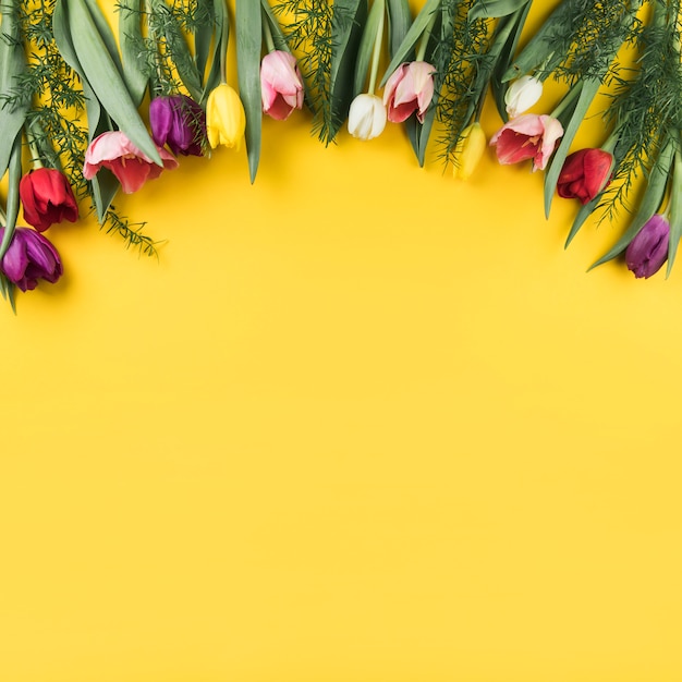 Free photo decoration of colorful tulips on yellow background with space for writing the text