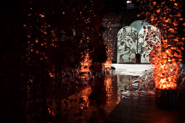 Decorations made of chrysanthemums on threads stand along glance path in dark hall