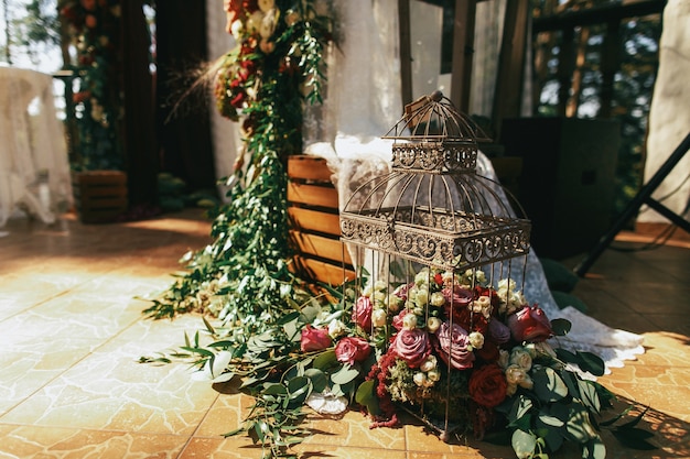 Decorative bird cage full of red roses, spearworts and greenery