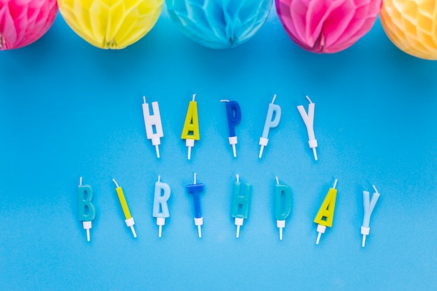 Free Photo decorative colorful paper balls and happy birthday text candles on blue background