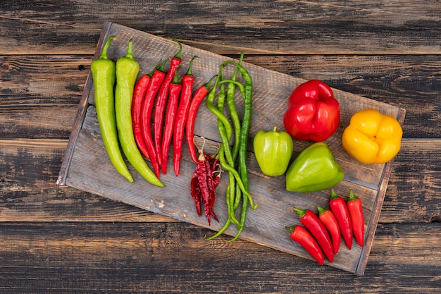 decorative composition with chili and sweet peppers top view on a wood cutting board on wood