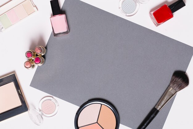 Decorative cosmetics around gray paper sheet