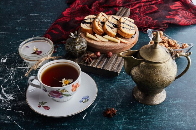 A decorative cup of herbal tea with rollcake slices.