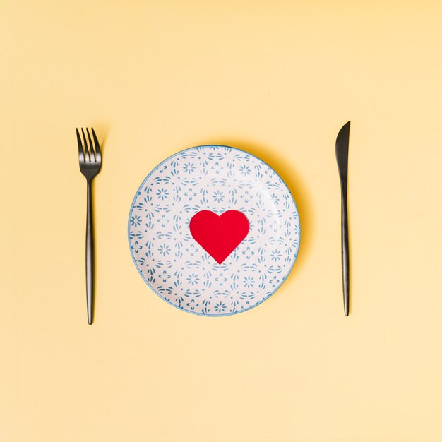 Decorative heart on beautiful plate between cutlery