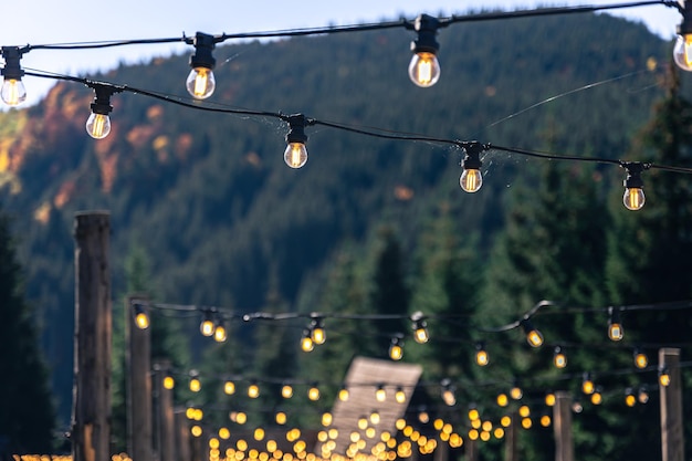 Decorative light bulbs on wooden poles in a mountainous area