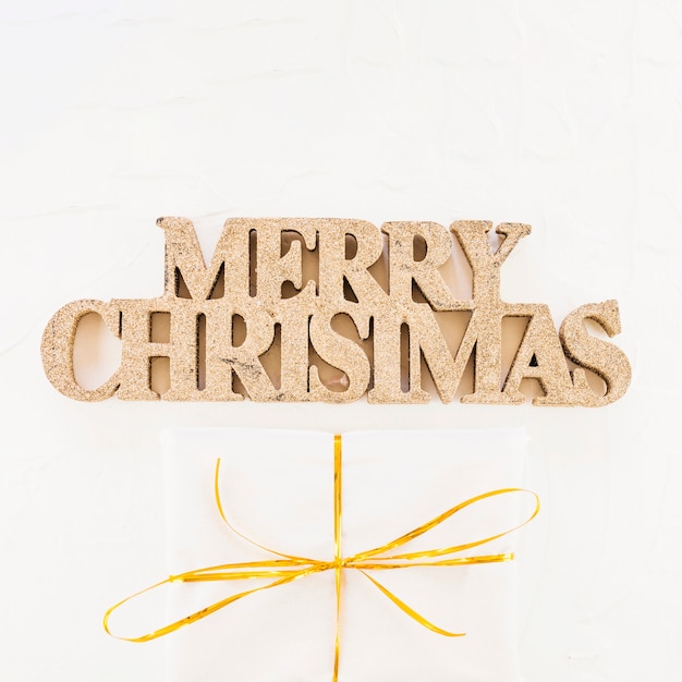 Free photo decorative merry christmas inscription near gift box in wrap