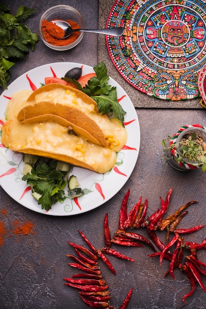 Free photo decorative mexican symbol on board near dried chili and pita with filling on plate