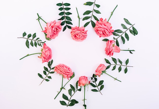 Free photo decorative pink roses arranged in heart shape on white backdrop