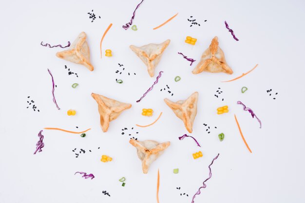 Decorative triangular dumpling with salad on white backdrop