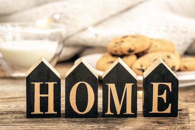 Free photo decorative word home on a blurred background with a glass of milk and cookies