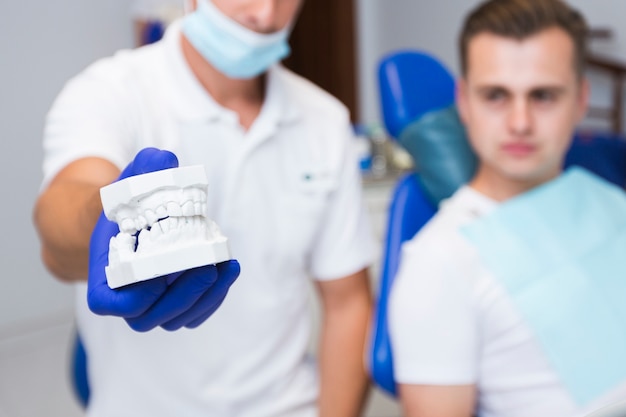 Defocused dentist holding dentures with patient