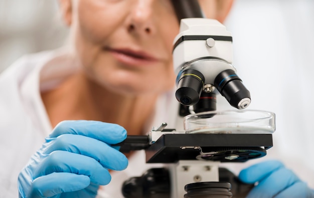 Free Photo defocused female scientist looking through microscope