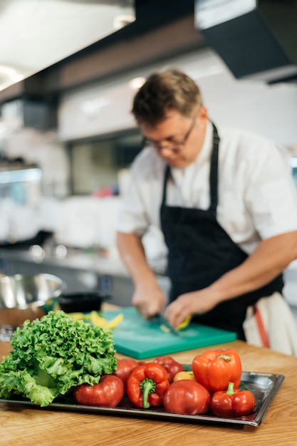 Free photo defocused male chef cutting vegetables