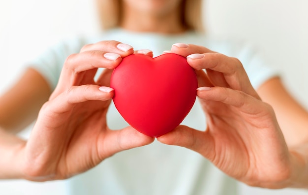 Free photo defocused woman holding heart shape