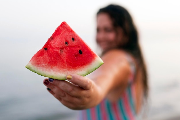 Free photo defocused woman in the water at the beach holding watermelon