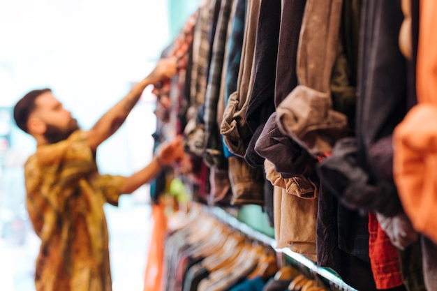 Free photo defocussed man choosing shirt from the rail in the shop