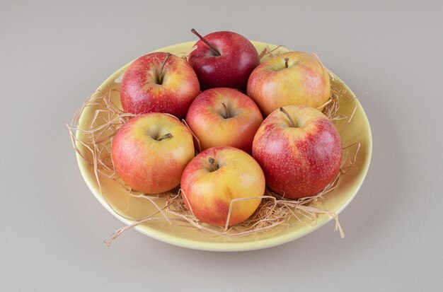 Delectable apples and straw in a bowl on marble 