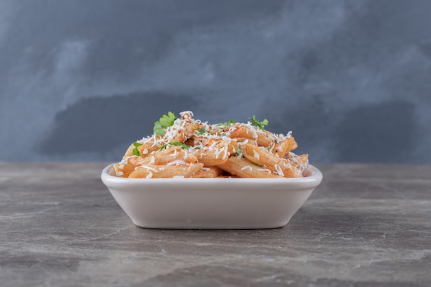 Delectable penne pasta in the bowl , on the marble surface.