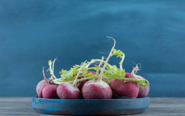 Delectable radishes in the bowl , on the marble table. 