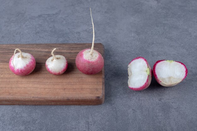 Delectable radishes with board , on the marble surface.