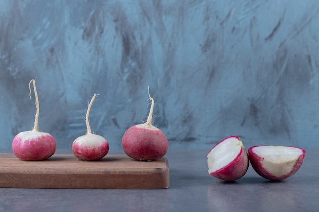 Delectable radishes with board , on the marble surface.