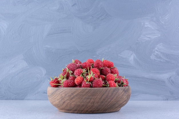 Free photo delectable raspberry pile in a wooden bowl on marble background. high quality photo