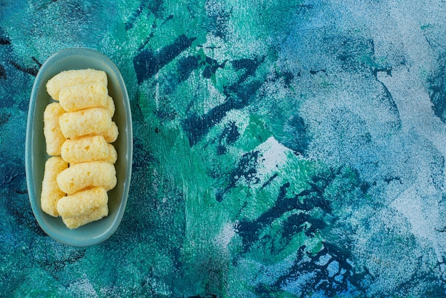 Delectable sweet corn sticks in a plate, on the blue table.