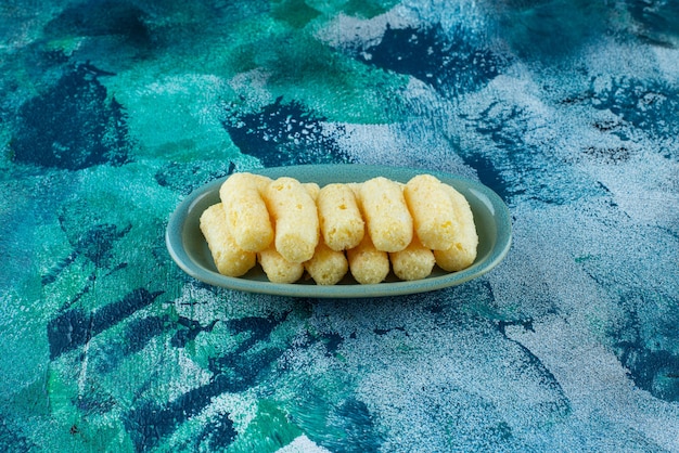 Free photo delectable sweet corn sticks in a plate, on the blue table.