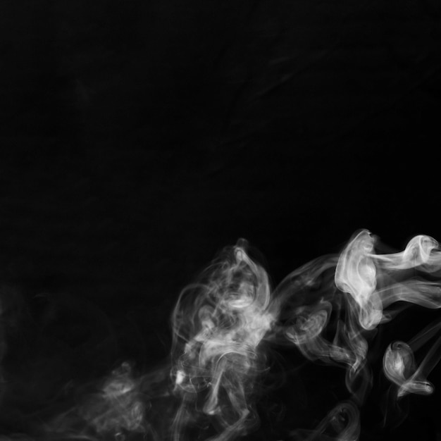 Delicate white cigarette smoke waves on black backdrop