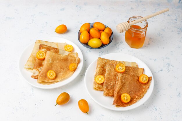 Delicious Breakfast. Orthodox holiday Maslenitsa. Crepes with cumquats and honet, top view