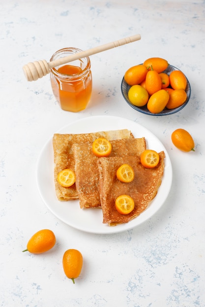 Delicious Breakfast. Orthodox holiday Maslenitsa. Crepes with cumquats and honet, top view