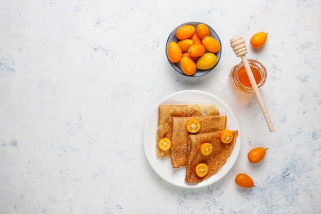 Delicious Breakfast. Orthodox holiday Maslenitsa. Crepes with cumquats and honet, top view