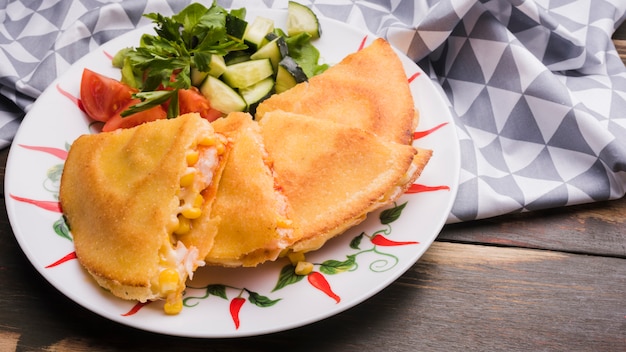 Delicious cake near vegetable salad on plate