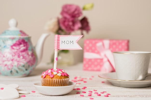 Delicious cake with decorative flag with mom title near teapot and cup