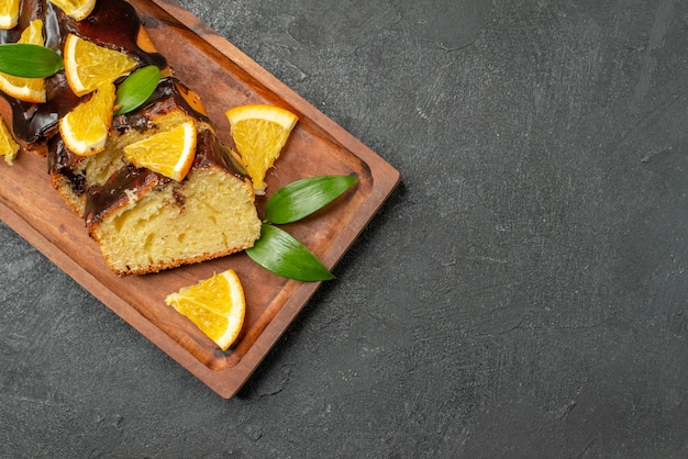 Free Photo delicious cakes decorated with orange and chocolate on wooden cutting board on black table