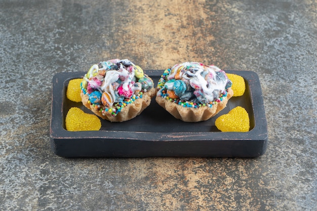 Free photo delicious cakes with heart shape candy on a dark wooden board