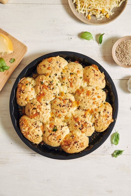 Delicious cheese bubble pizza bread with ingredients and cheese on a white table