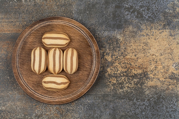 Free Photo delicious chocolate striped biscuits on wooden plate.