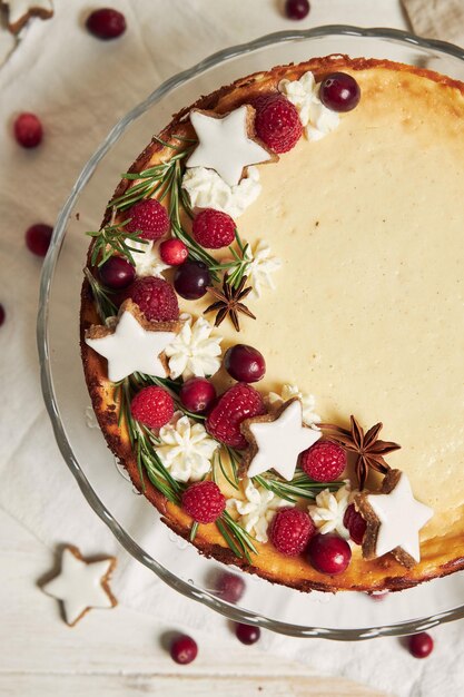 Delicious Christmas cheesecake with cranberries and cookies stars on a white table