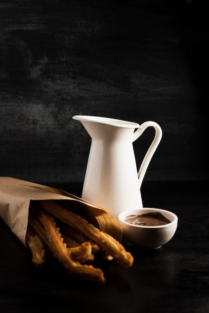 Delicious churros in a paper bag and melted chocolate