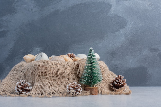 Free photo delicious cookies bundled on a piece of cloth amid christmas decorations on marble surface