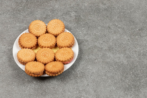 Delicious cookies filled with cream on white plate