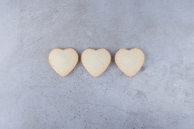 Delicious cookies in heart shaped placed on a stone table.