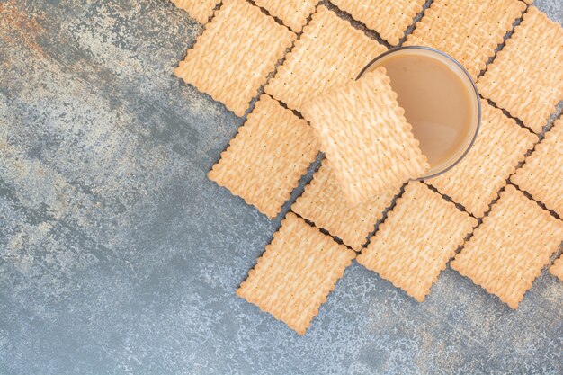 Delicious crackers with cup of coffee on marble background. High quality photo